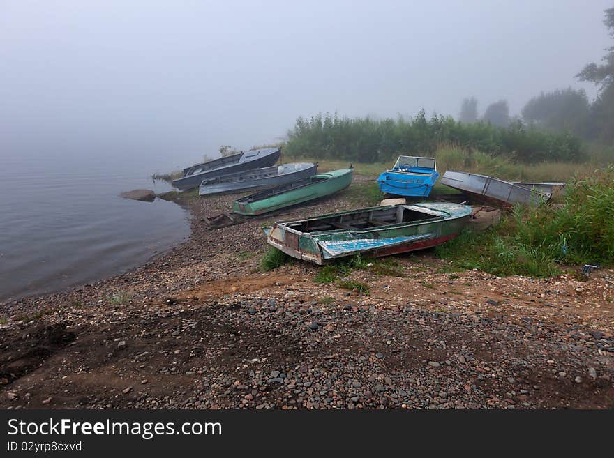 Old boats at the foggy riverbank