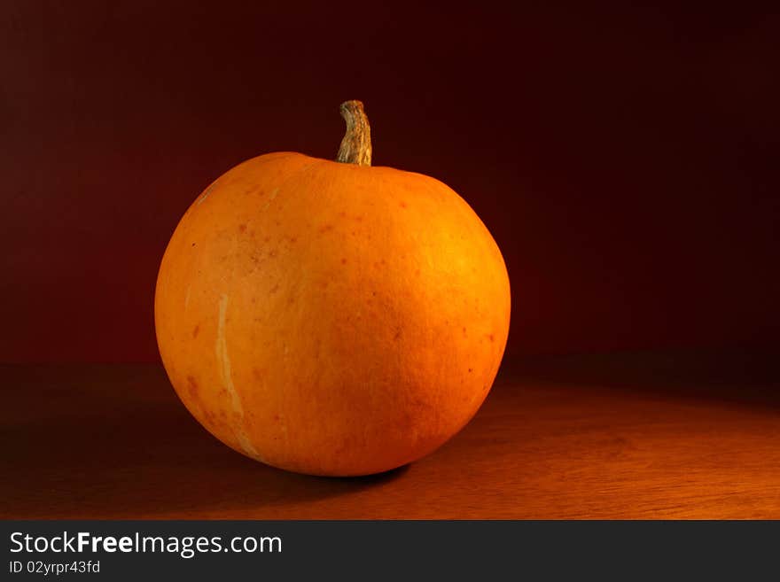 A pumkin on a table with side lighting. A pumkin on a table with side lighting.