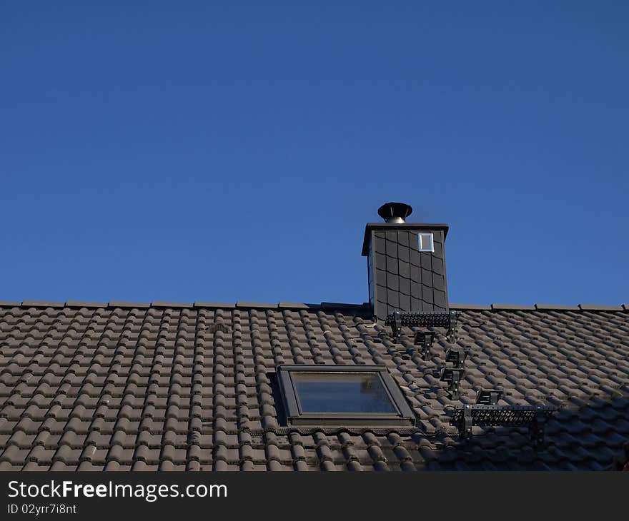 Gray roof and chimney in the blue sky