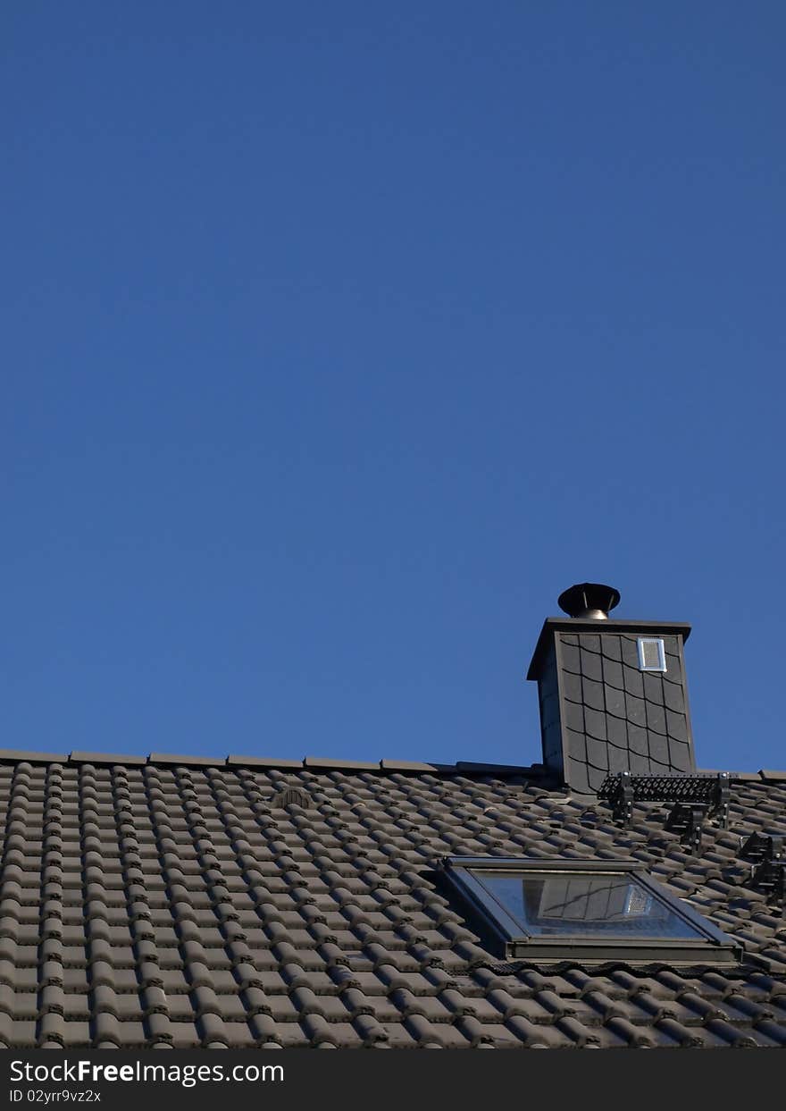 Gray roof and chimney in the blue sky