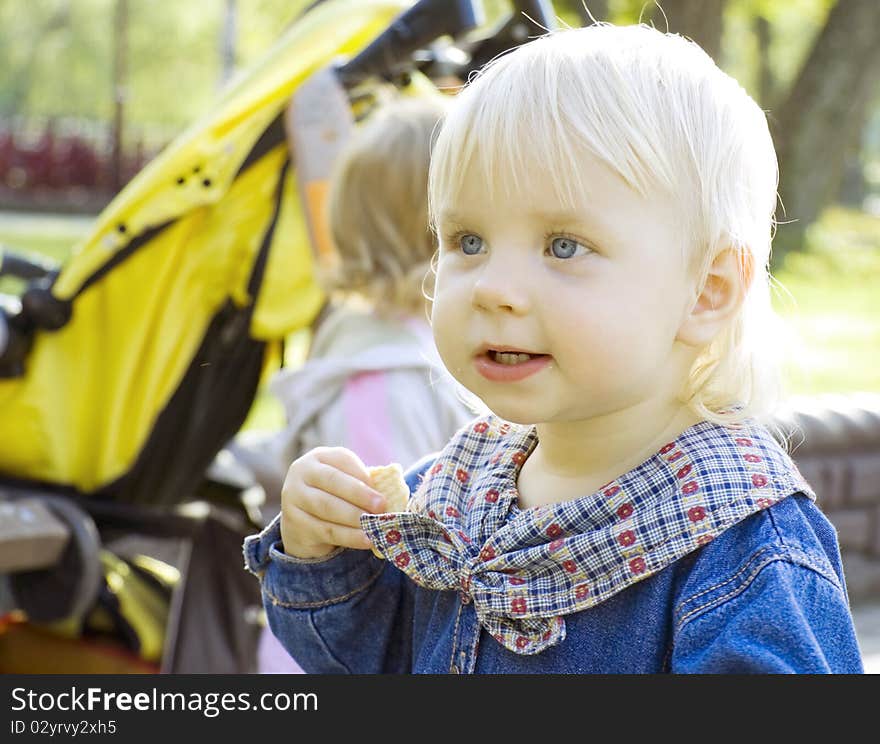 The fair-haired girl with blue eyes with curiosity looks in a distance and eats cookies. The fair-haired girl with blue eyes with curiosity looks in a distance and eats cookies