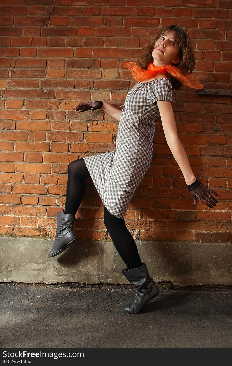 City streets. Girl at a brick wall.