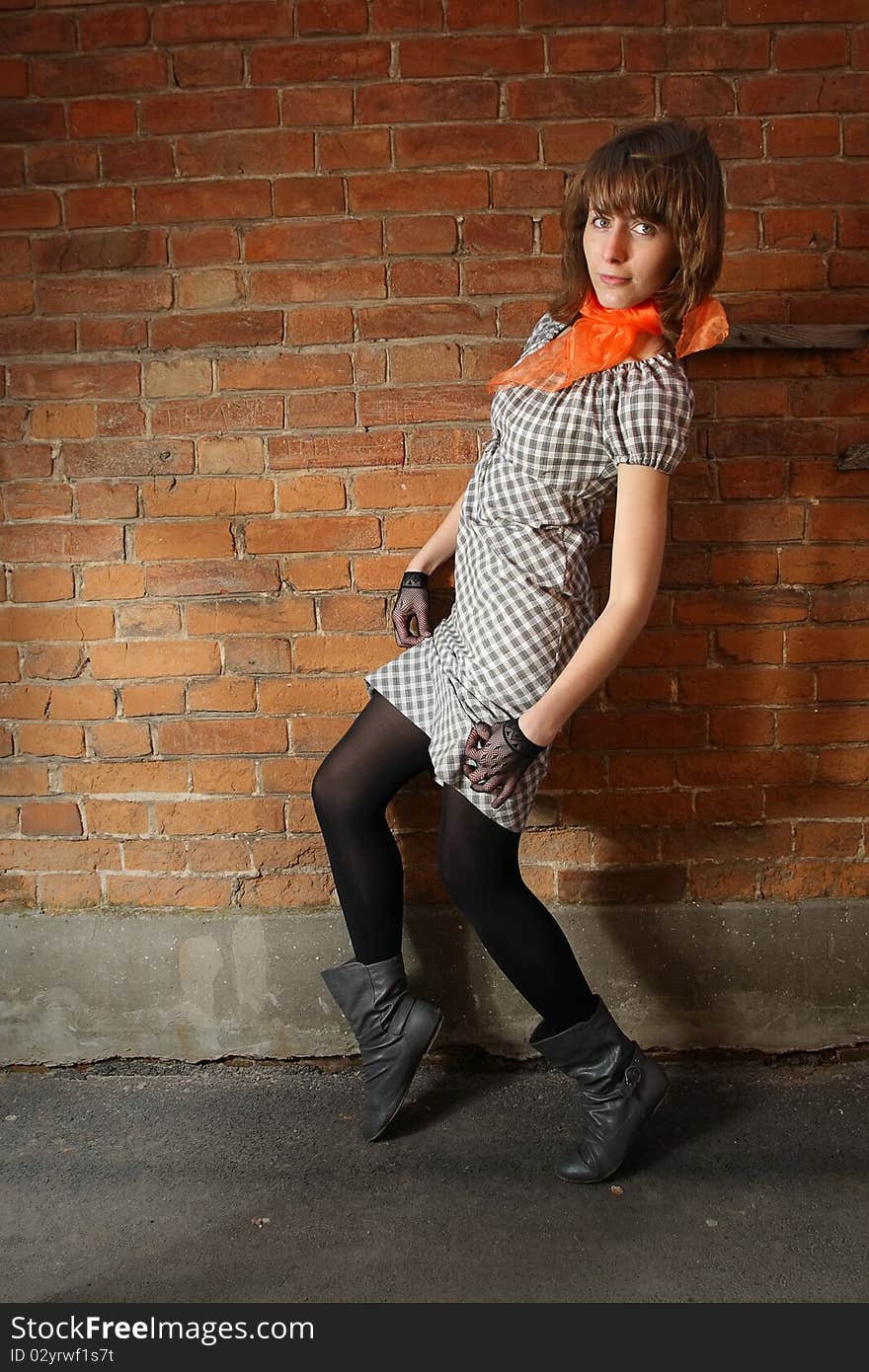 City streets. Girl at a brick wall.