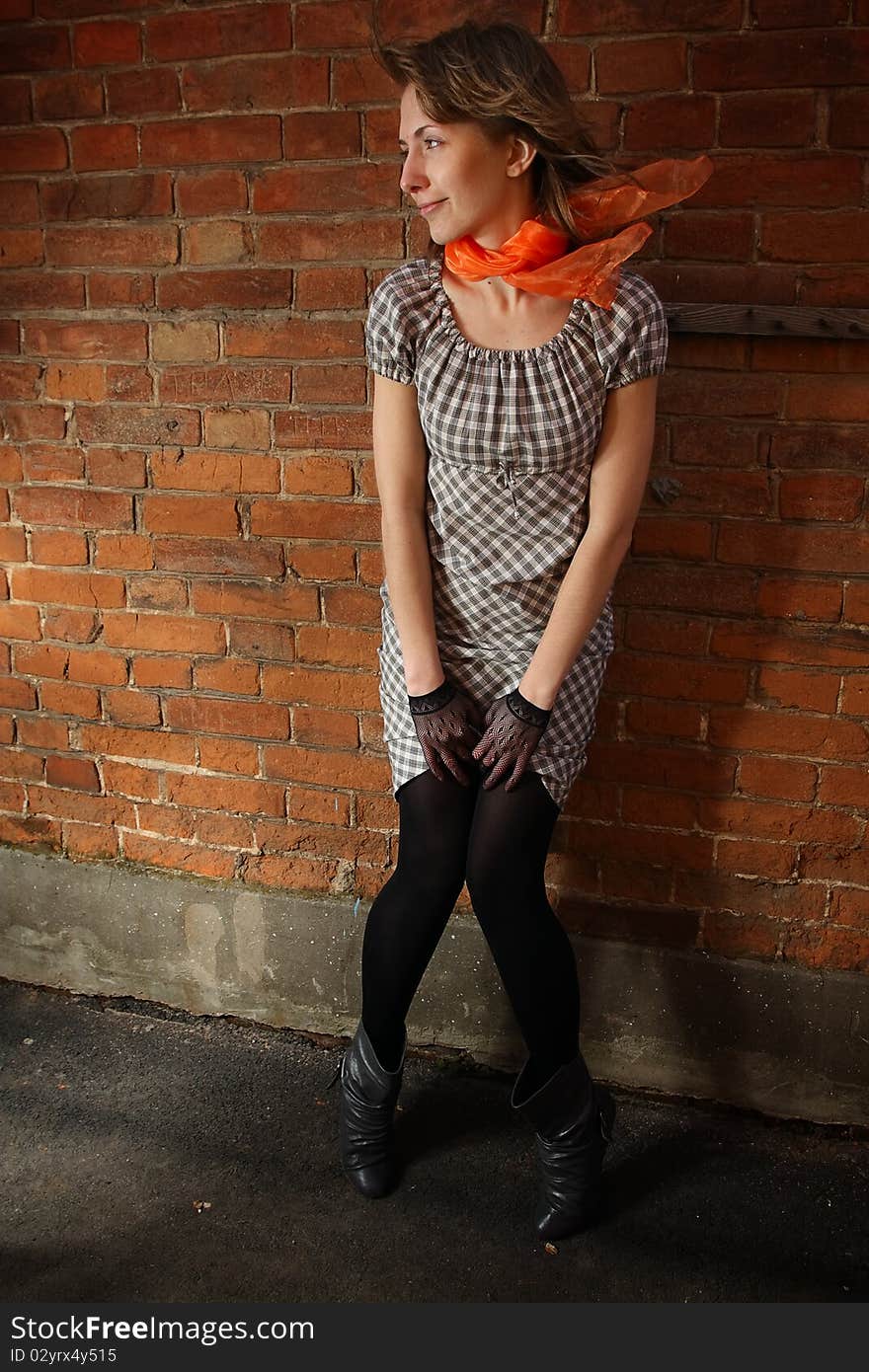 City streets. Girl at a brick wall.