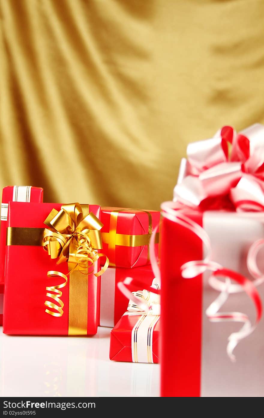 A lot of Christmas presents different values in the red packages with colorful bows on a gold background. A lot of Christmas presents different values in the red packages with colorful bows on a gold background