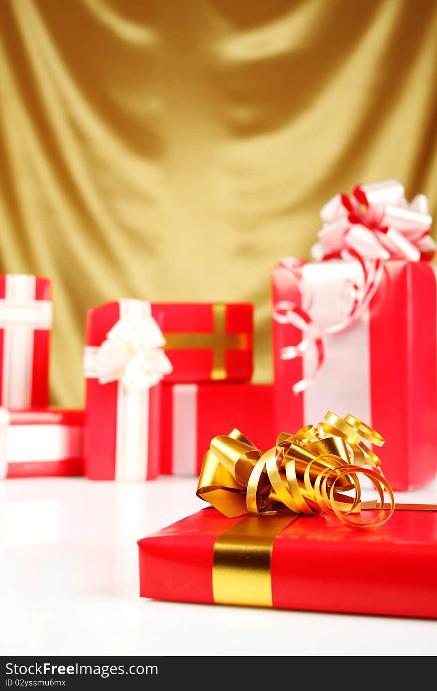 A lot of Christmas presents different values in the red packages with colorful bows on a gold background. A lot of Christmas presents different values in the red packages with colorful bows on a gold background