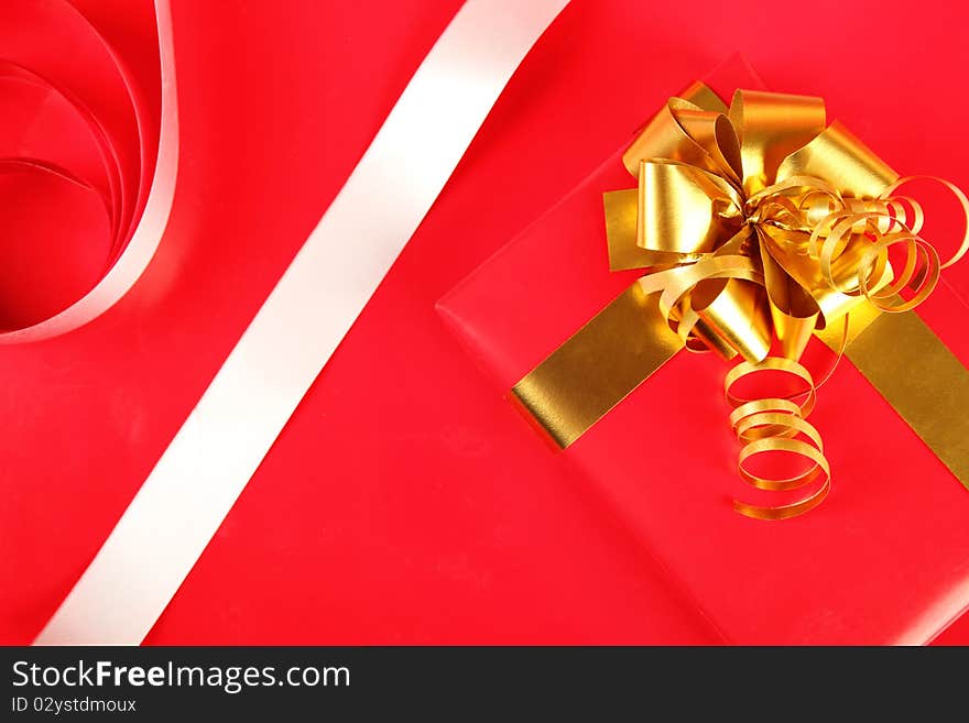 Big red gift with a golden ribbon and bow close up