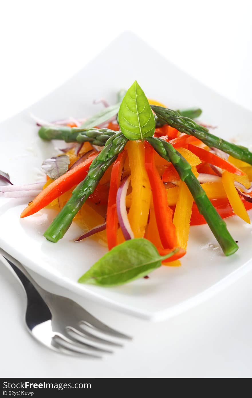 Vegetable salad with asparagus and pepper on white plate