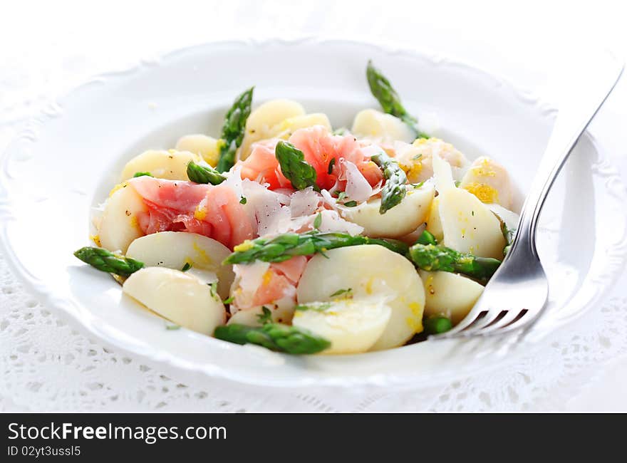 Prosciutto with asparagus and potatoes on white plate