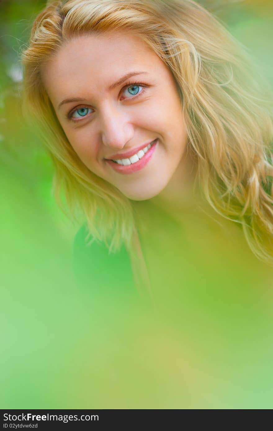 Portrait of young blonde through foliage.