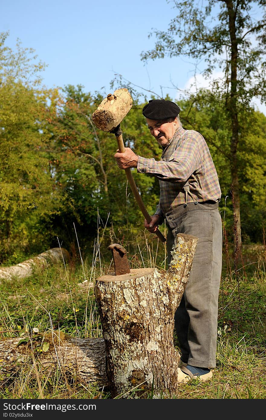 An old farmer who is splitting wood. An old farmer who is splitting wood.