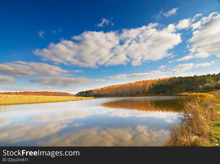 Azure lake, autumnal wood and the blue sky with clouds. Azure lake, autumnal wood and the blue sky with clouds.