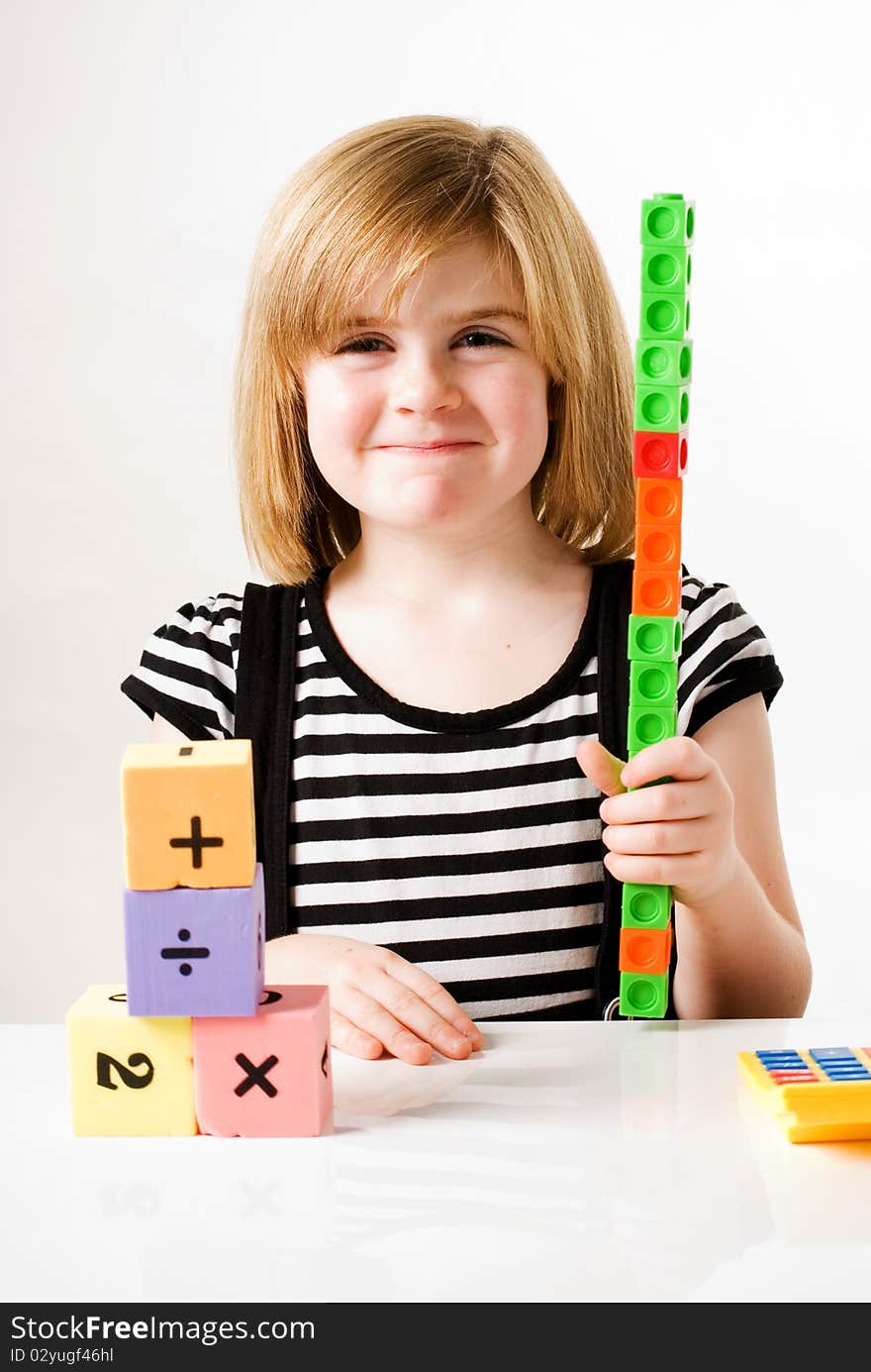 A vertical image of a young girl playing and stacking numbered building blocks. A vertical image of a young girl playing and stacking numbered building blocks