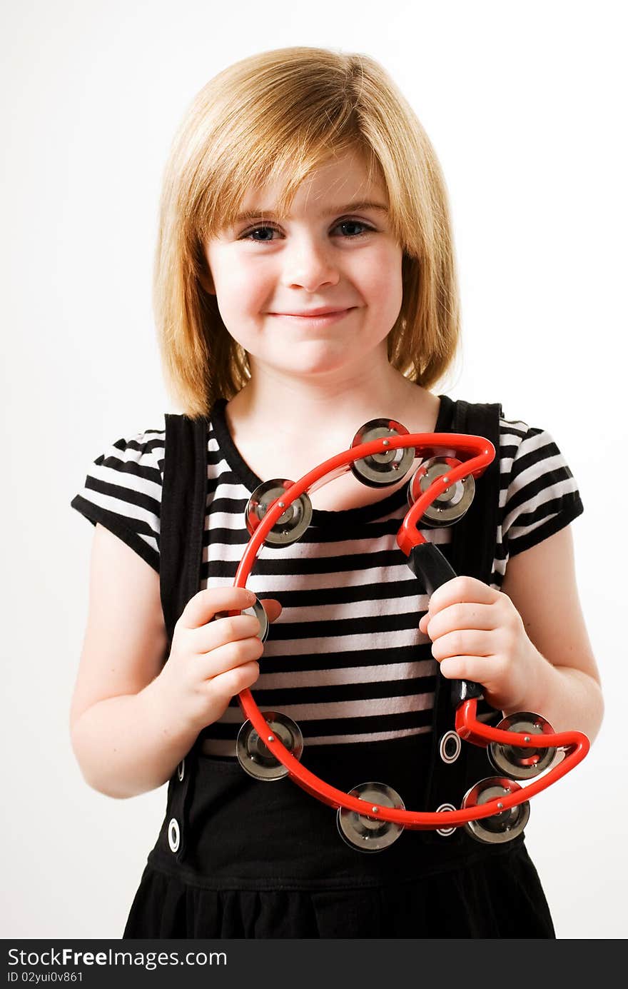 A horizontal image of a young female playinga red cresent shaped tambourine. A horizontal image of a young female playinga red cresent shaped tambourine