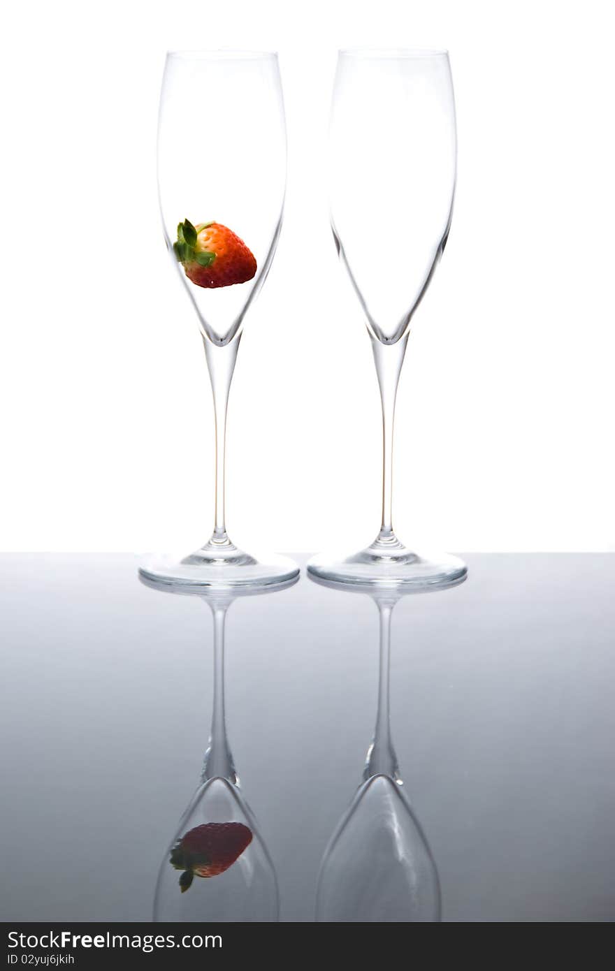 Two sparkling wine glasses with a single strawberry. Two sparkling wine glasses with a single strawberry