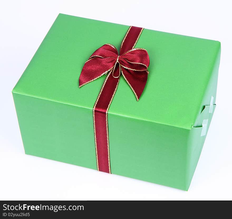 Gift in green wrapping with a red bow on white background