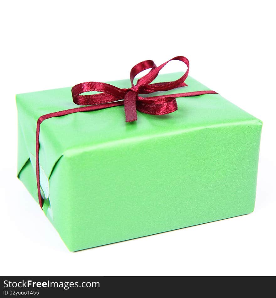 Gift in green wrapping with a red bow on white background