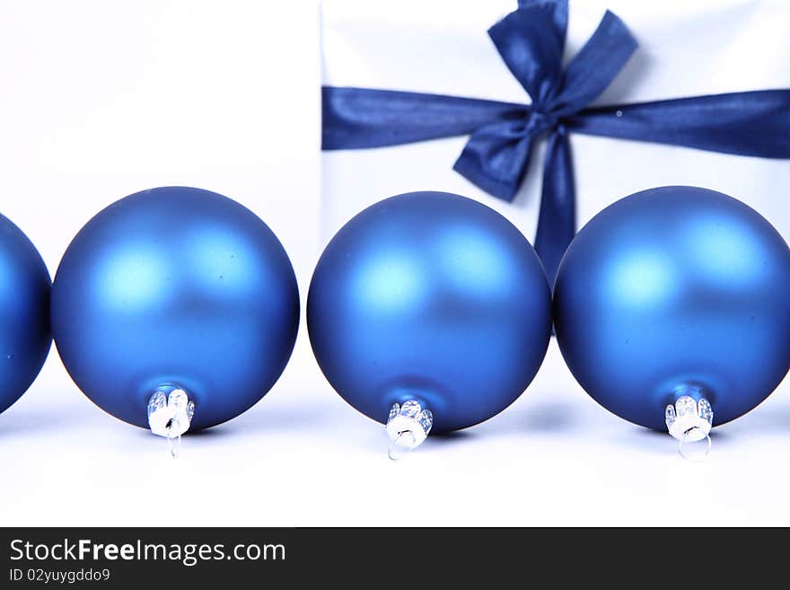 Blue matt christmas balls and a gift in red wrapping on white background, with space for your text. Blue matt christmas balls and a gift in red wrapping on white background, with space for your text