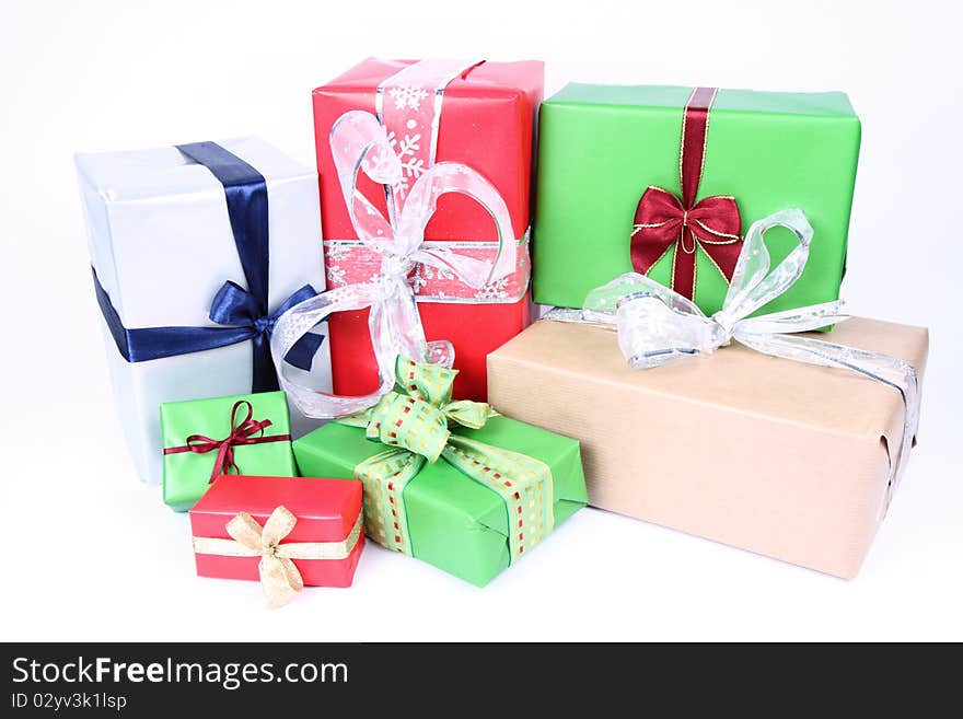 Gifts in silver, green, brown and red wrapping with bows on white background. Gifts in silver, green, brown and red wrapping with bows on white background