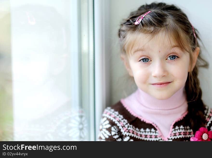 Beauty small girl with long dark braid and big blue eyes in winter sweater