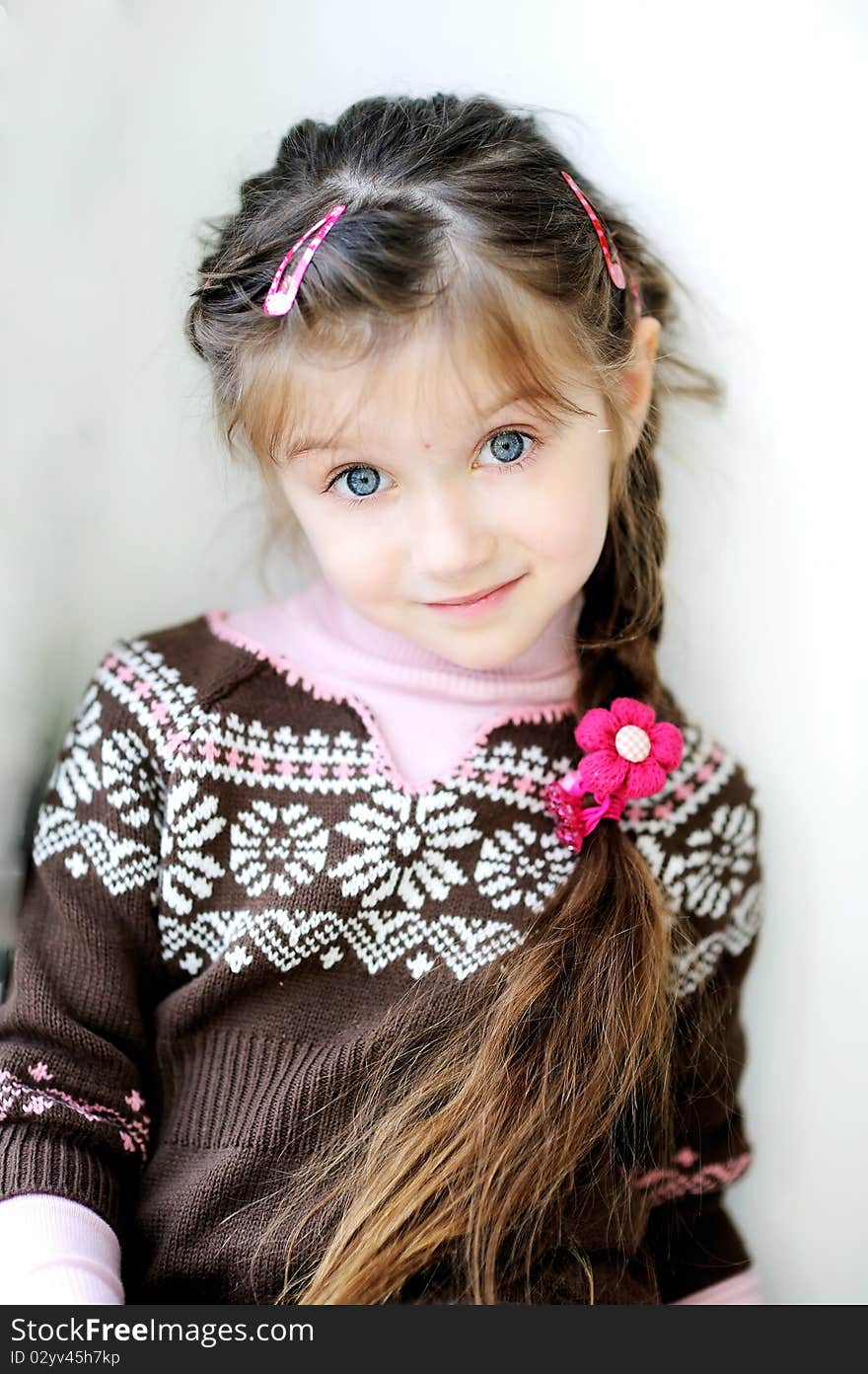 Beauty small girl with long dark braid and big blue eyes in winter sweater