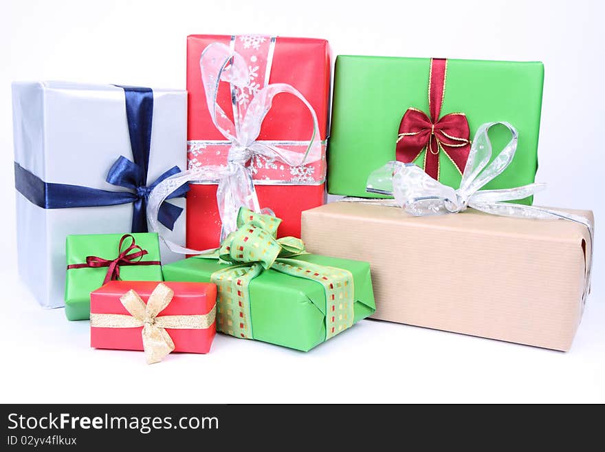 Gifts in silver, green, brown and red wrapping with bows on white background. Gifts in silver, green, brown and red wrapping with bows on white background