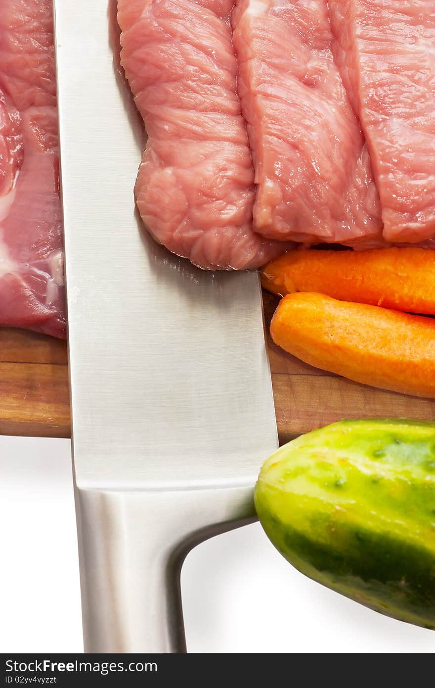 Unprepared meat and vegetables on a cutting board.