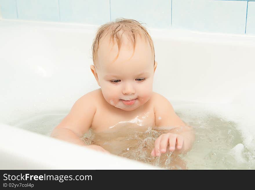 Cute adorable baby clapping on water in foam bath