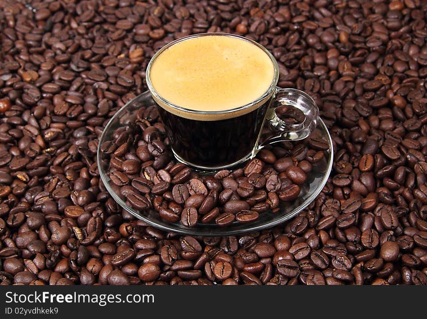 Espresso in a transparent cup on the background of coffee beans