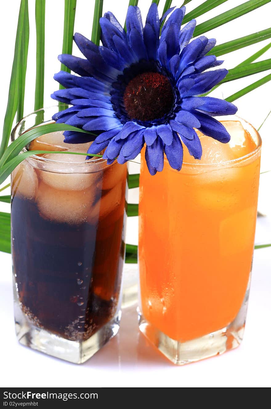 Orange and cola drink glasses with gerbera flower isolated on white background. Orange and cola drink glasses with gerbera flower isolated on white background.