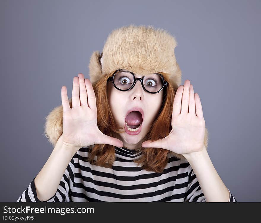 Funny girl in winter cap and glasses. Studio shot.