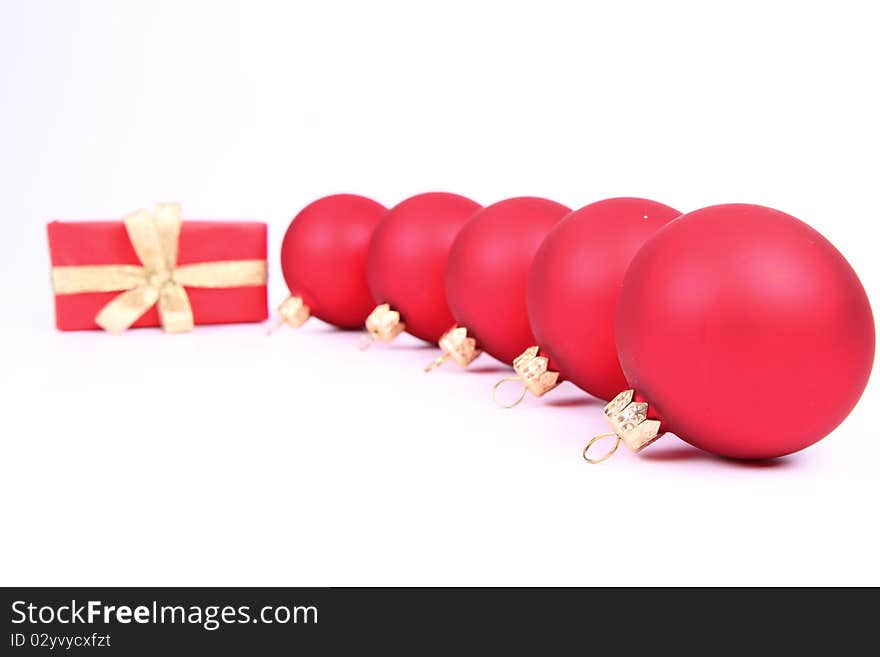 Red matt christmas balls and a gift in red wrapping on white background, with space for your text. Red matt christmas balls and a gift in red wrapping on white background, with space for your text