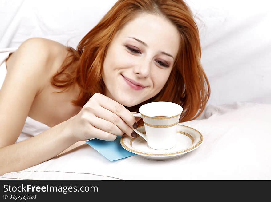 Woman lying in the bed near cup of coffee.