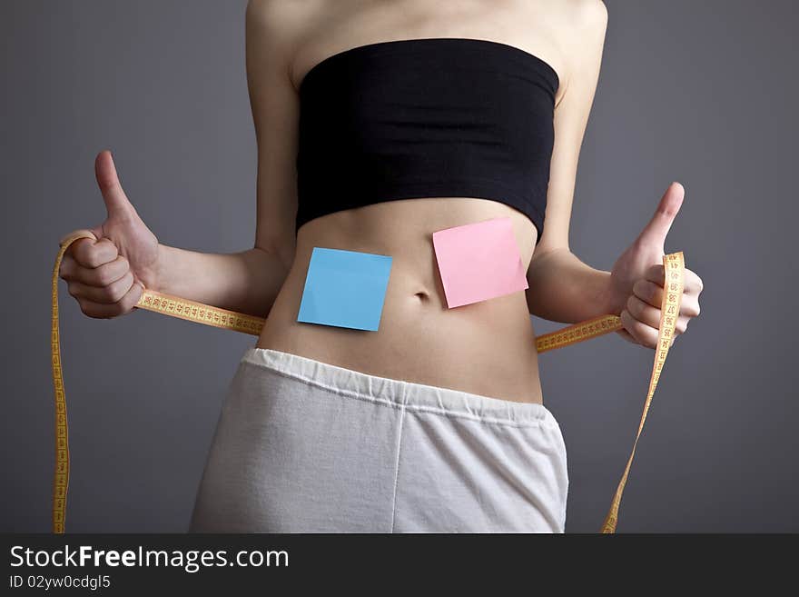 Beautiful and strong women's abs with metre and note. Studio shot.