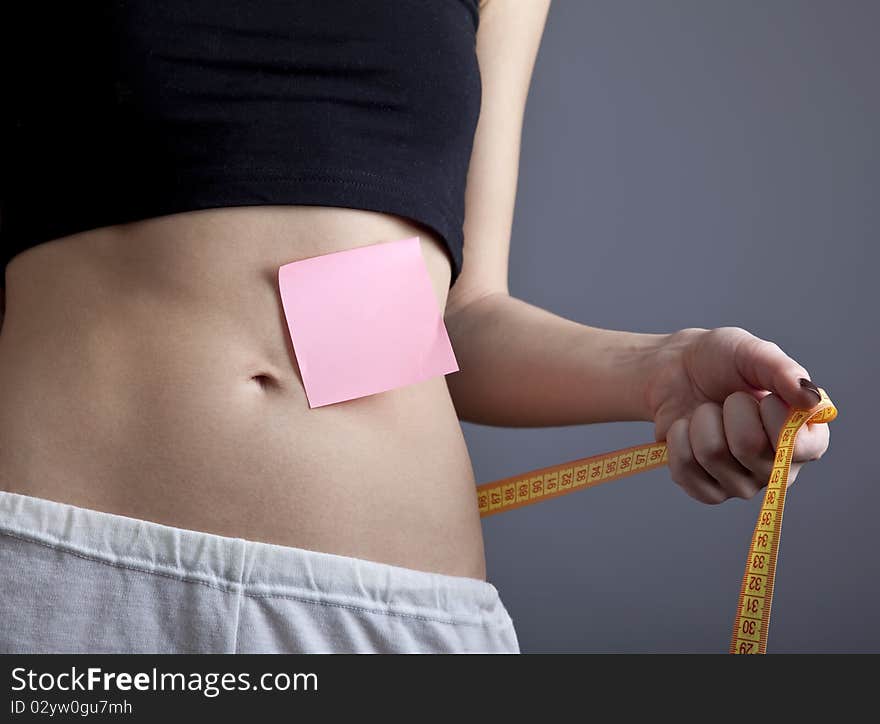 Beautiful and strong women's abs with metre and note. Studio shot.