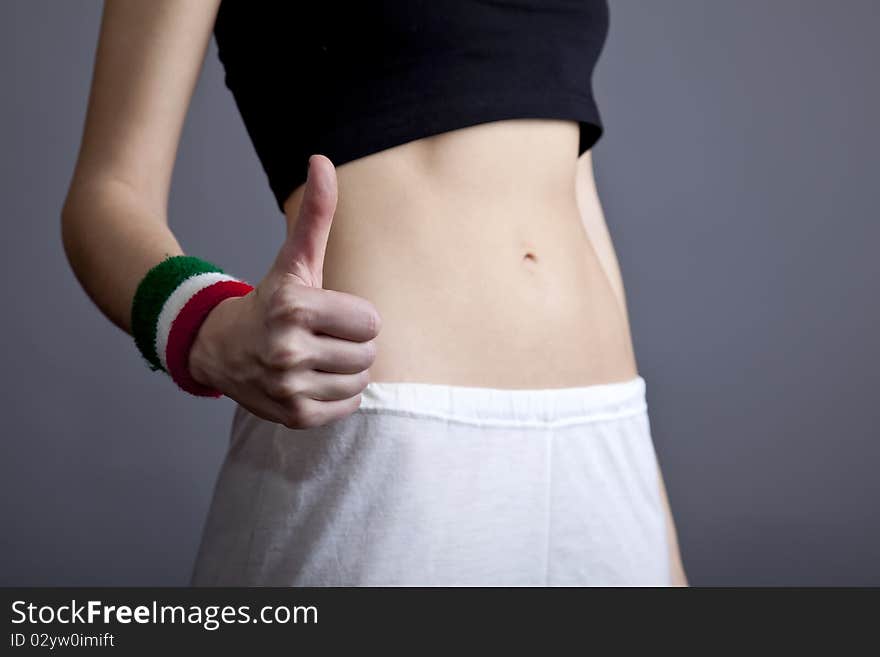 Beautiful and strong women's abs show hand OK. Studio shot.