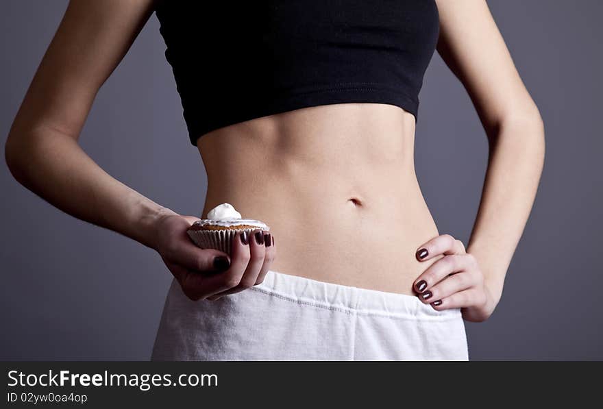 Beautiful and strong women's abs with metre and cake. Studio shot. Beautiful and strong women's abs with metre and cake. Studio shot.