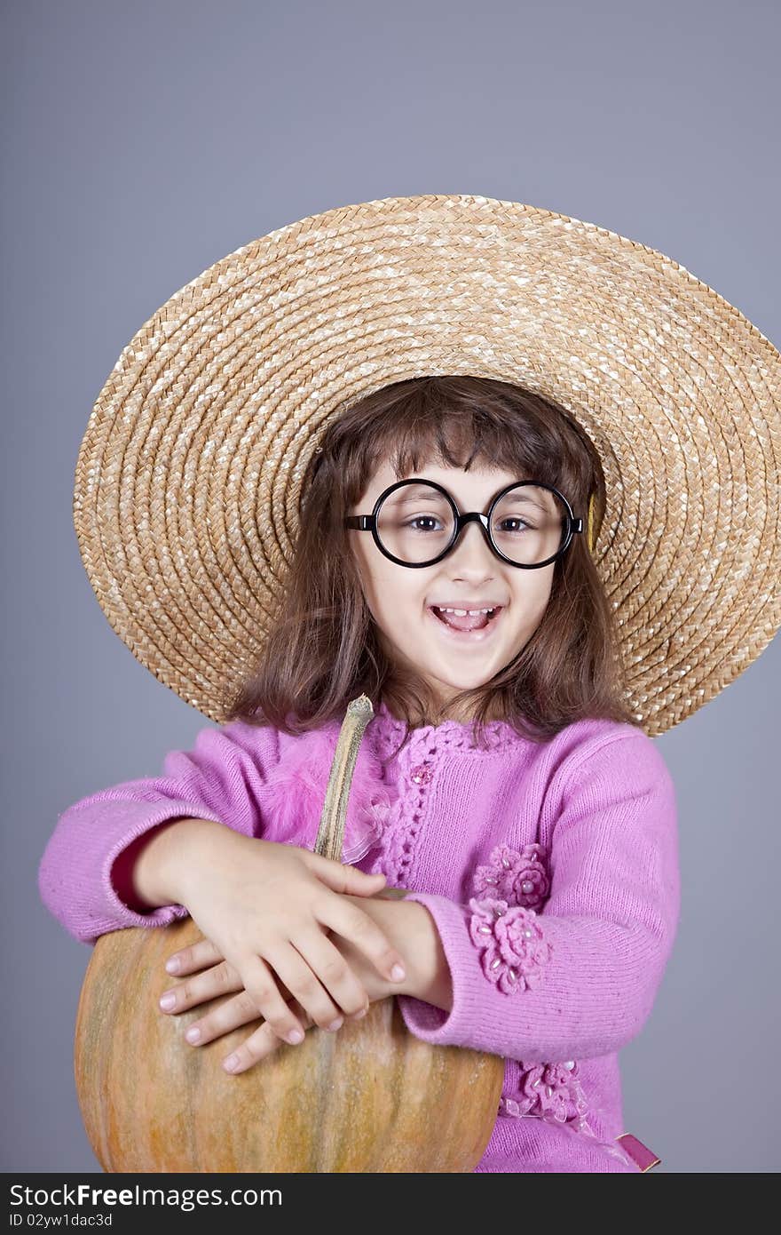 Funny girl in cap and glasses keeping pumpkin.