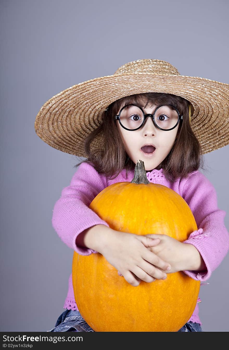 Funny girl in cap and glasses keeping pumpkin.