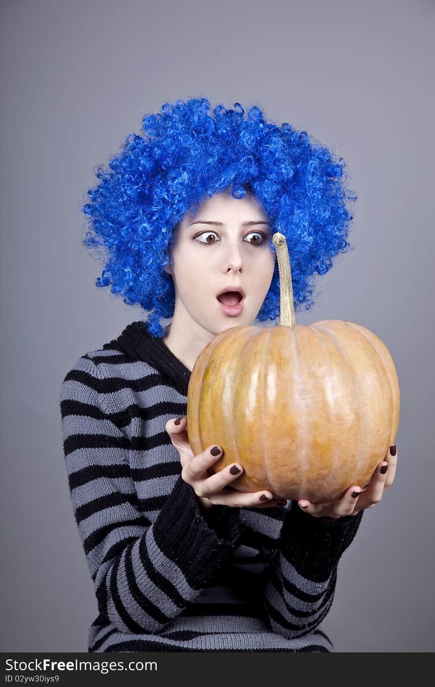 Funny girl with blue hair keeping pumpkin. Studio shot.