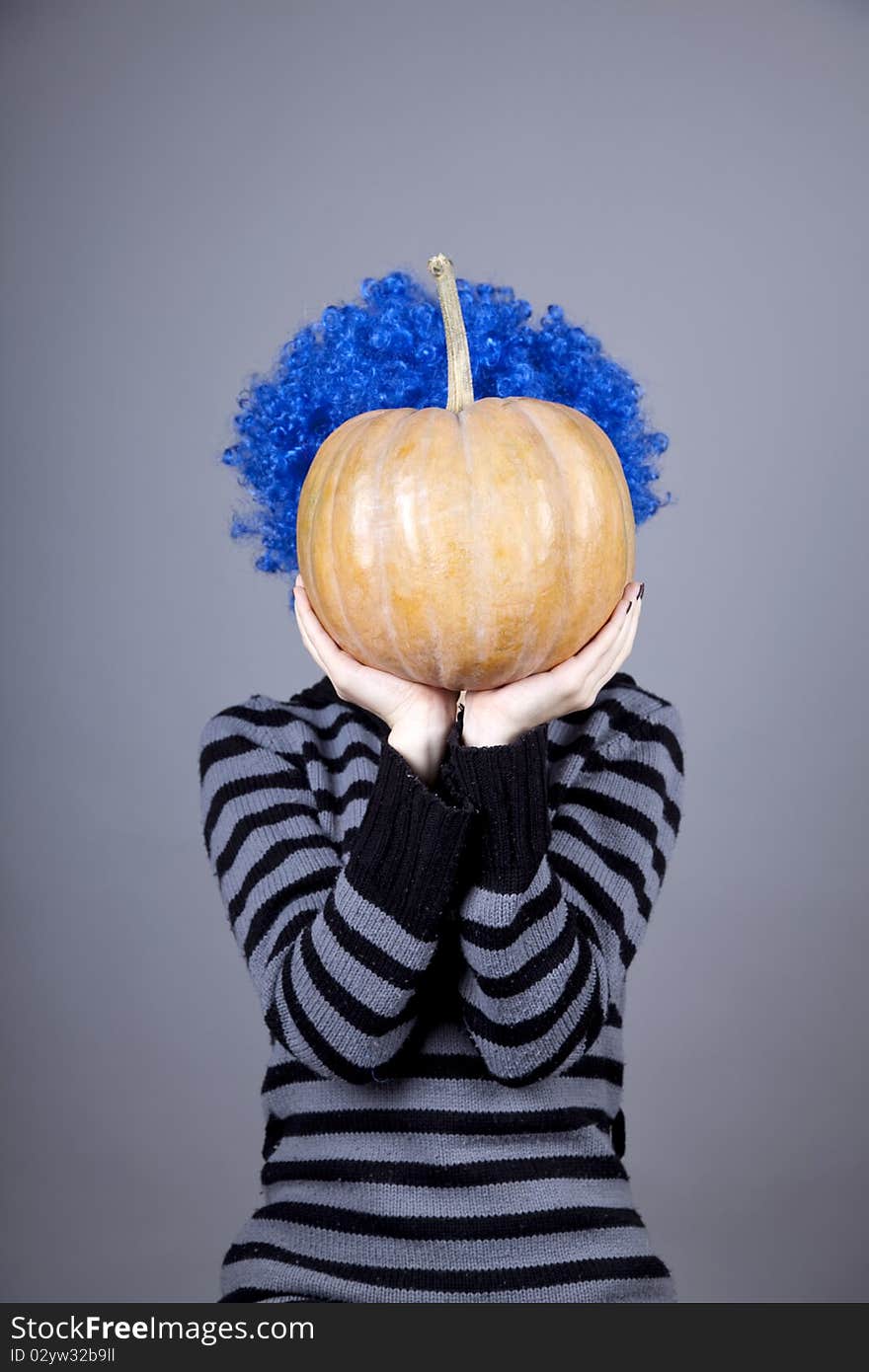 Funny girl with blue hair keeping pumpkin. Studio shot.