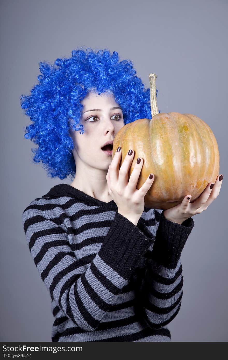 Funny girl with blue hair keeping pumpkin. Studio shot.