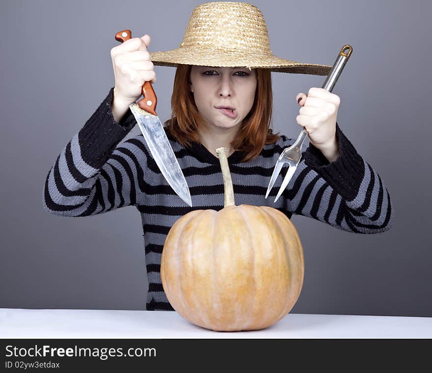 Funny girl in cap try to eat a pumpkin.