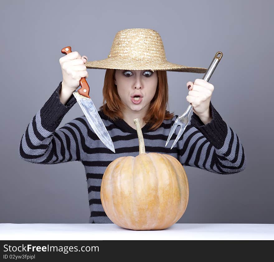 Funny girl in cap try to eat a pumpkin.