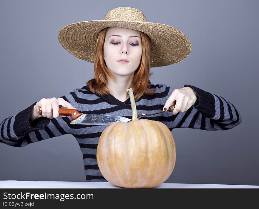 Funny girl in cap try to eat a pumpkin.