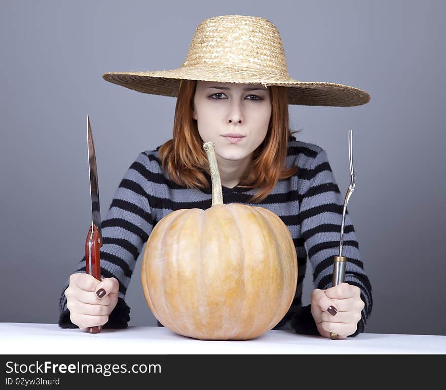 Funny girl in cap try to eat a pumpkin.