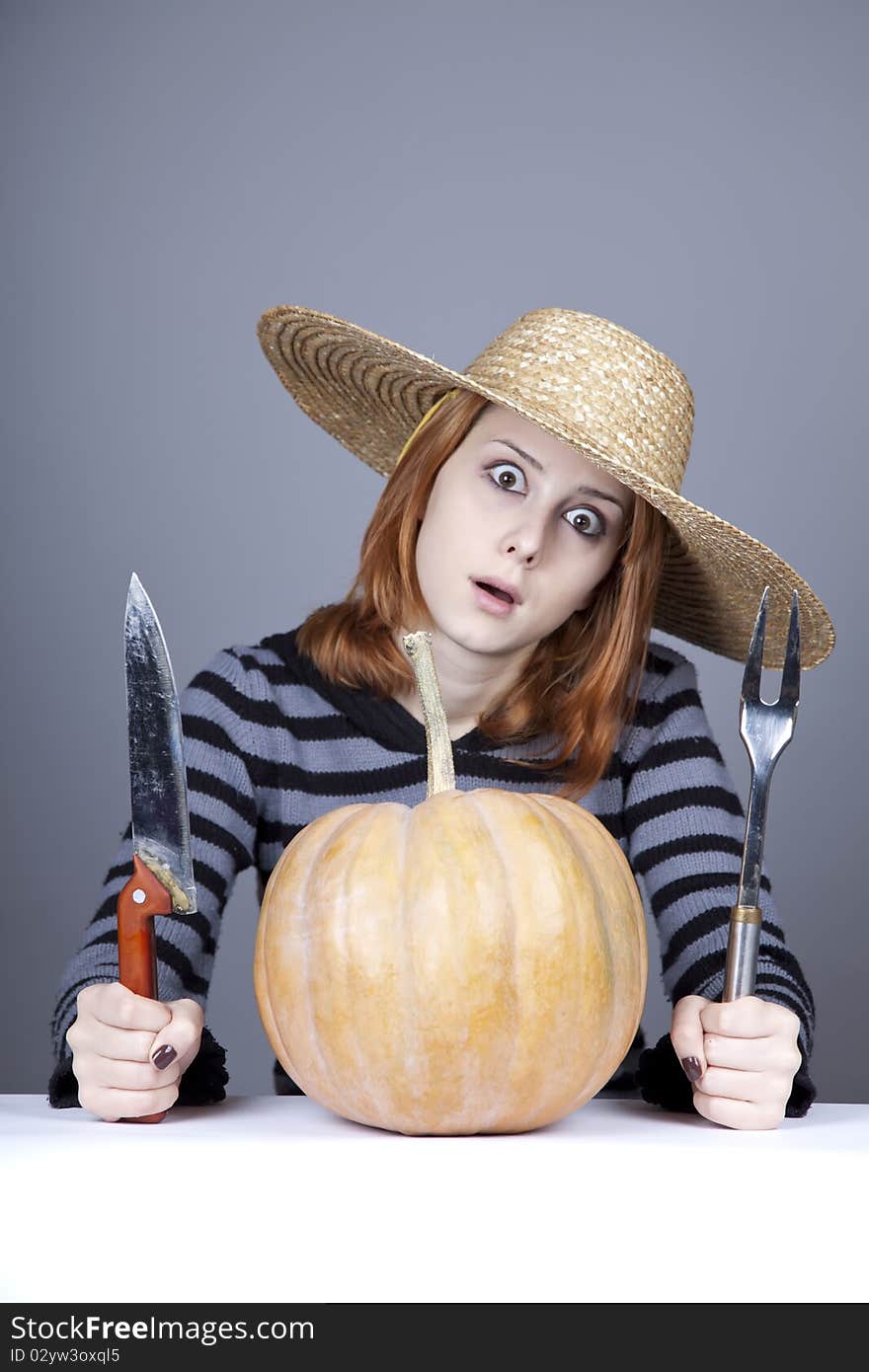 Funny girl in cap try to eat a pumpkin.