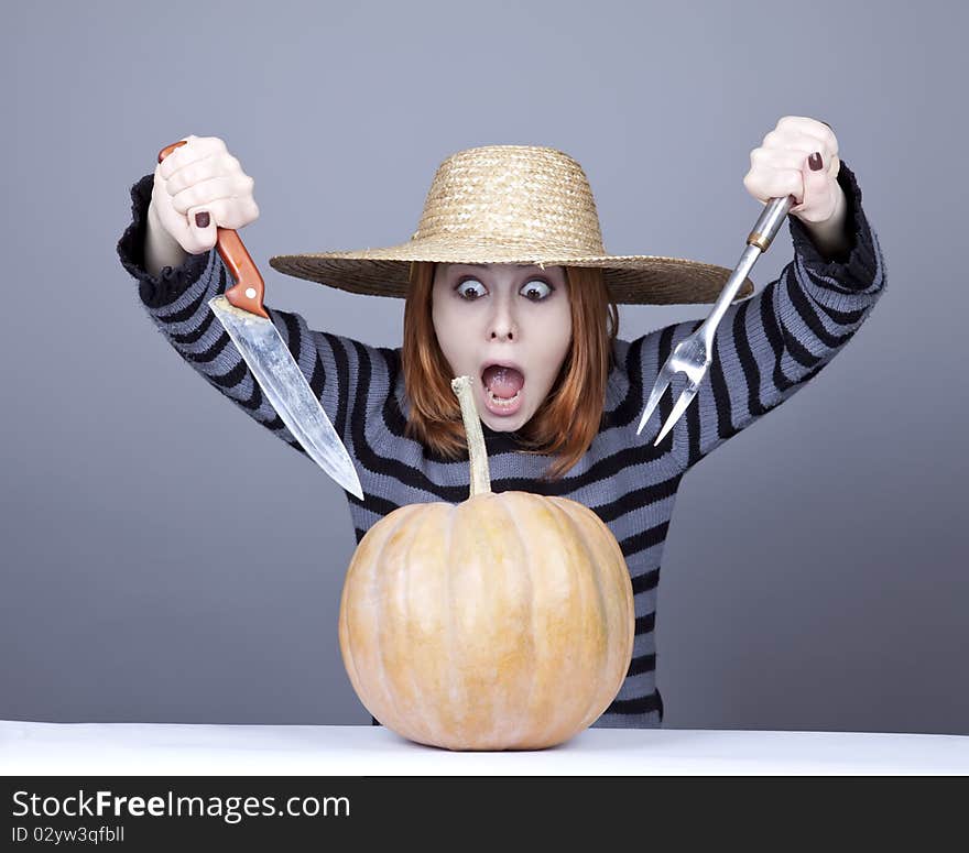 Funny girl in cap try to eat a pumpkin.