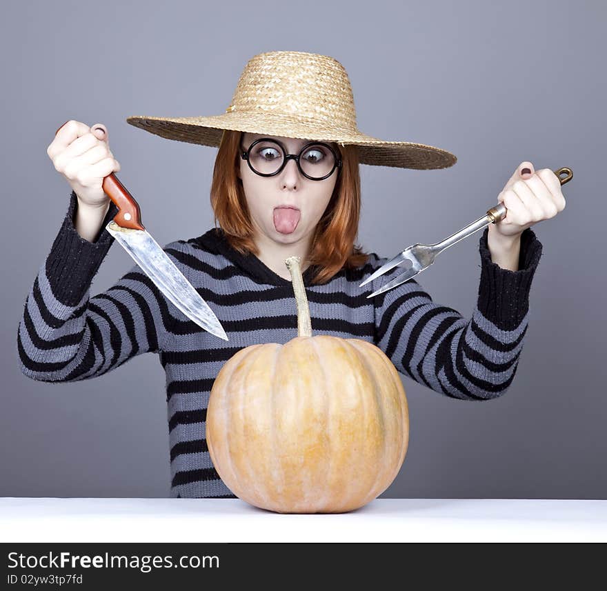 Funny girl in cap and fork with knife try to eat a pumpkin. Studio shot. Funny girl in cap and fork with knife try to eat a pumpkin. Studio shot.