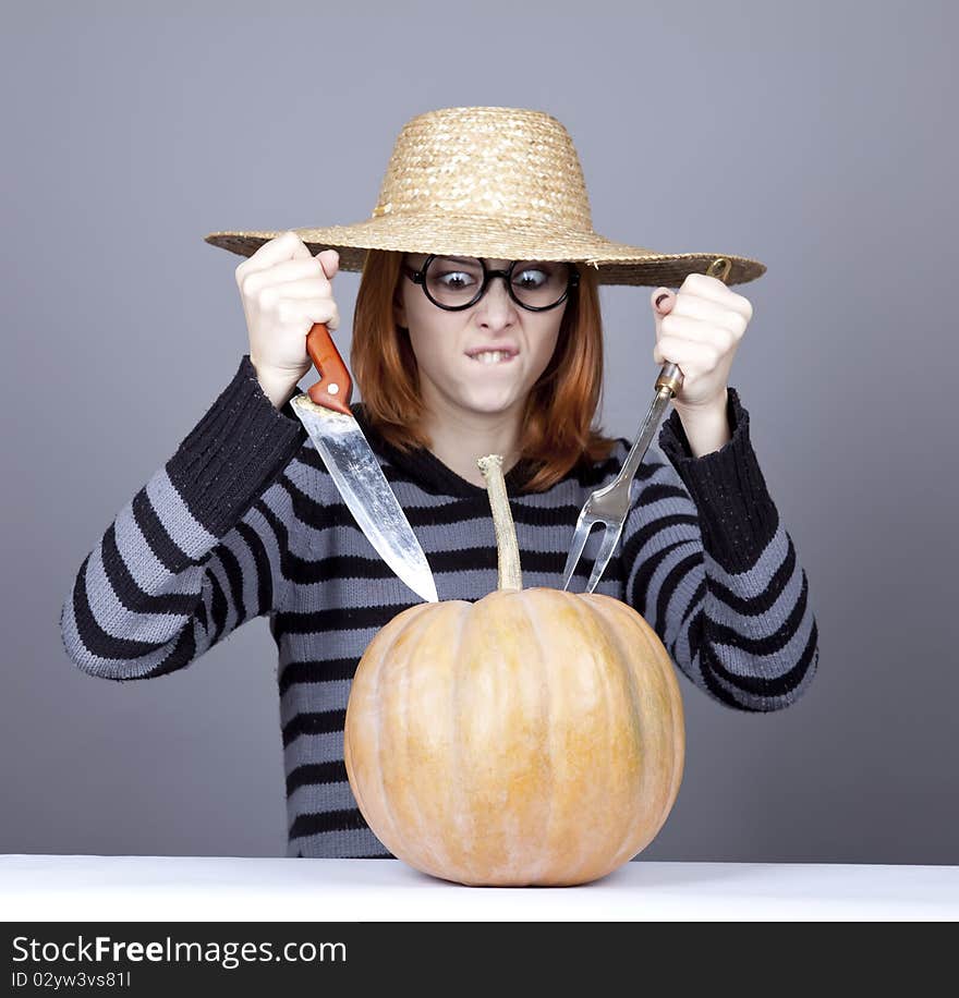 Funny girl in cap try to eat a pumpkin.